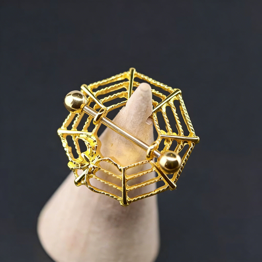 Close-up of a gold spider web nipple shield showcased on a jewelry display cone