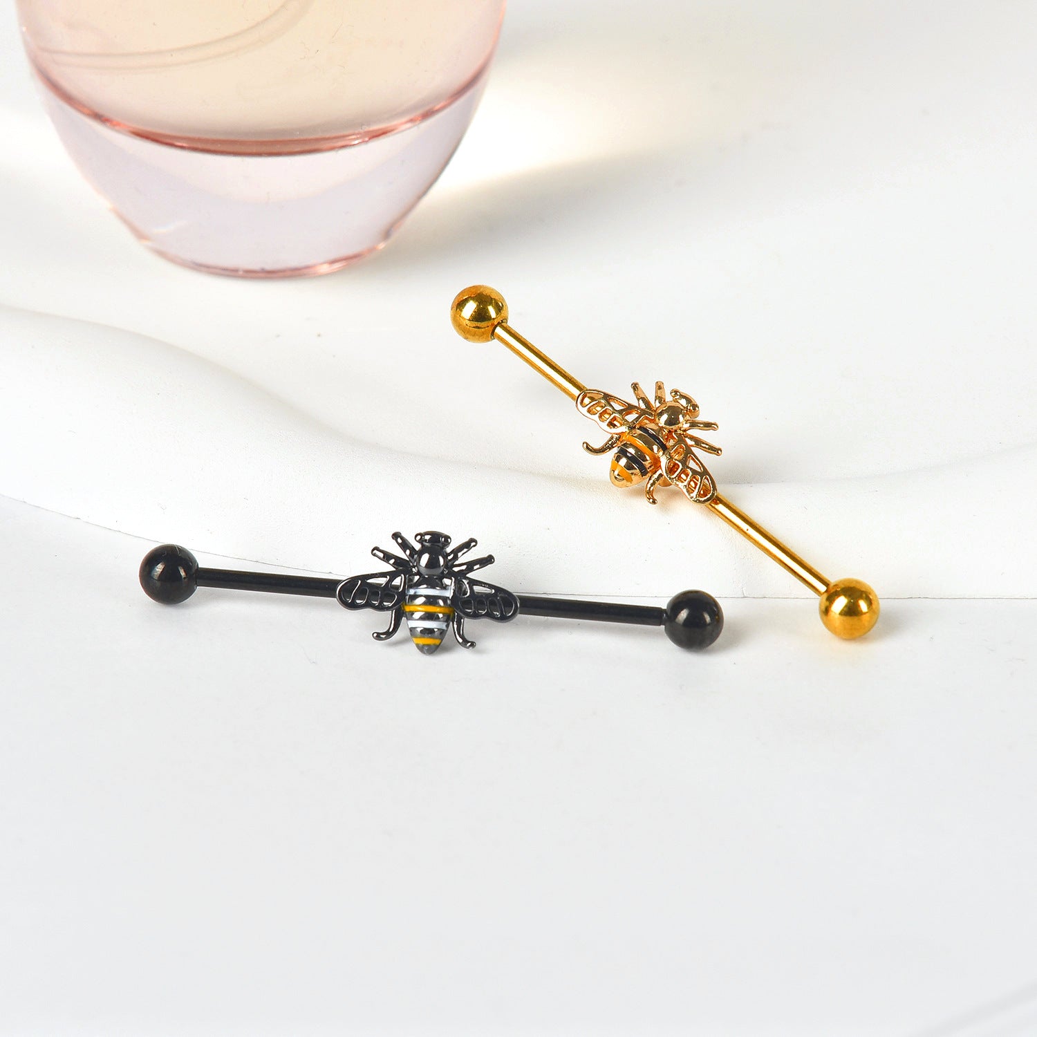 Close up of a black bee industrial bar in the foreground and a gold bee scaffold barbell in the background