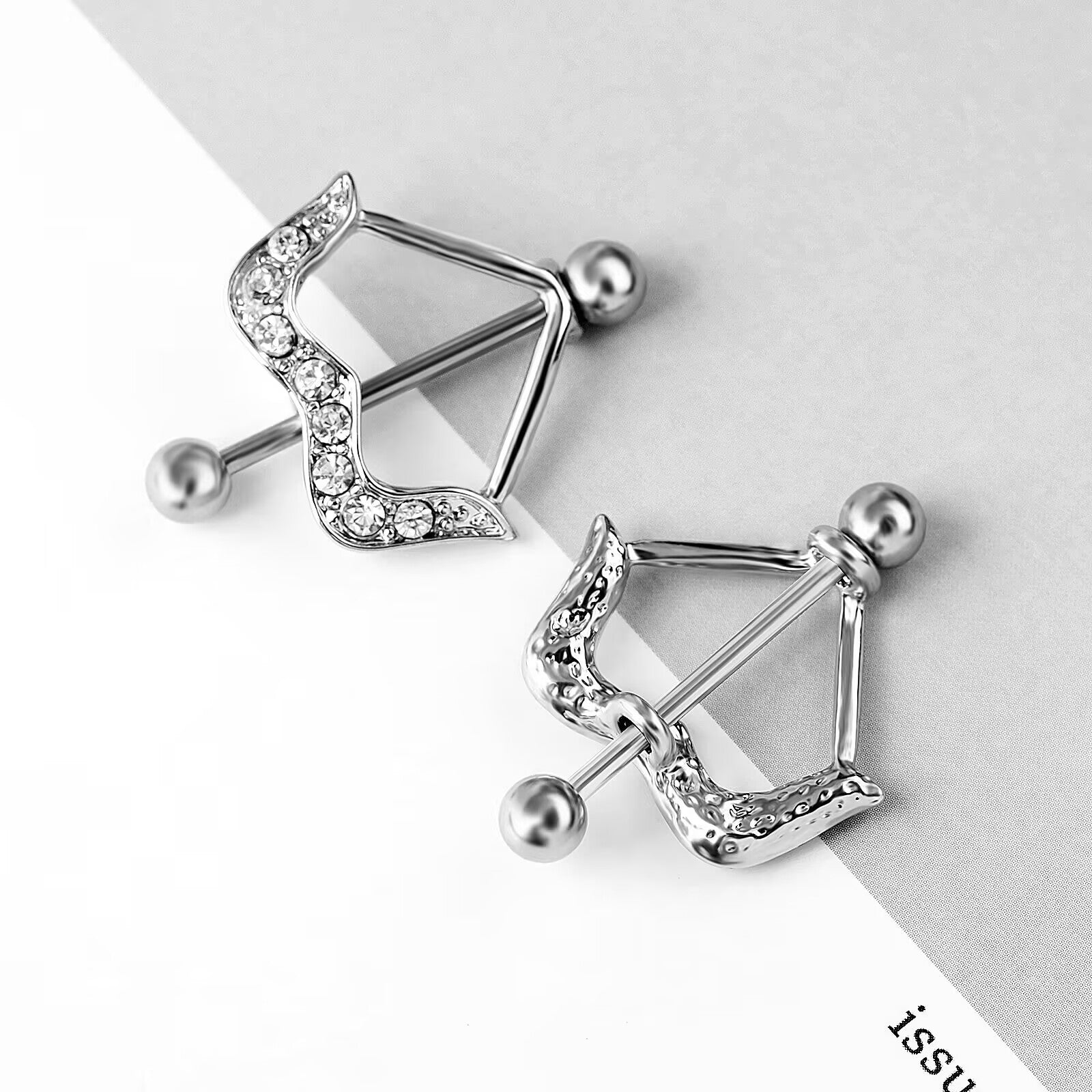 Aesthetic flat lay of bow-shaped nipple piercing jewelry on a minimalist background.